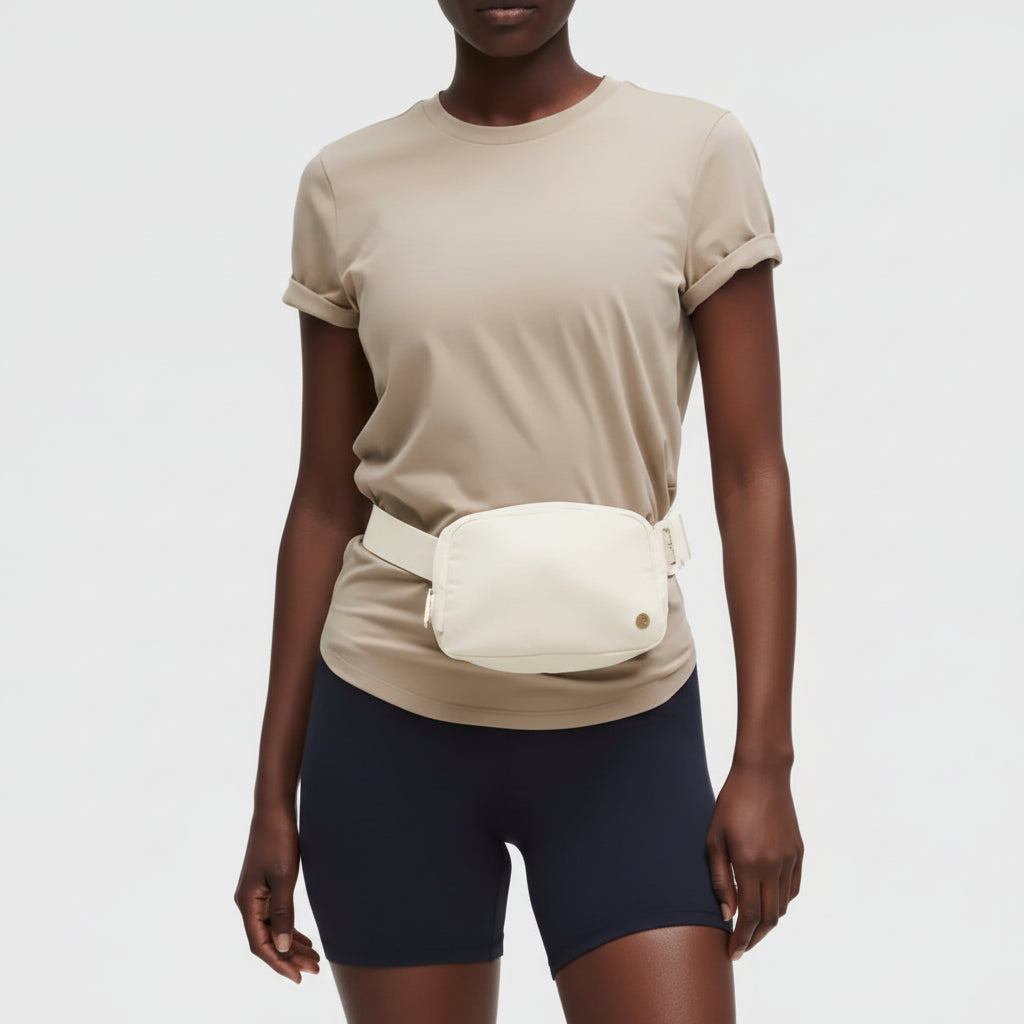Person wearing a beige top and black shorts with a white waist bag on a light gray background