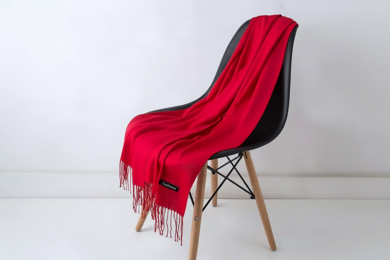 Red blanket draped over a white chair with a plant in the background