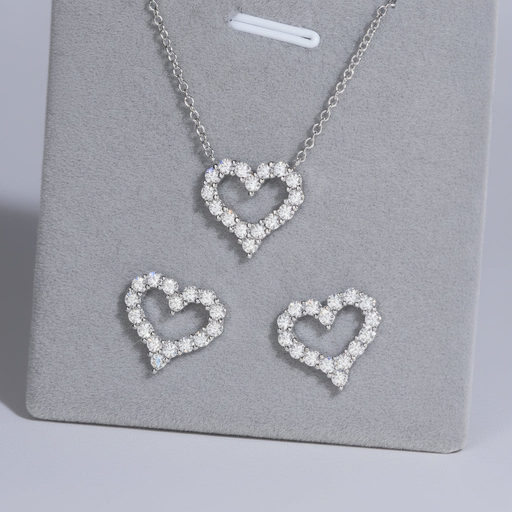 Heart-shaped jewelry set with necklace and earrings on a gray stand.