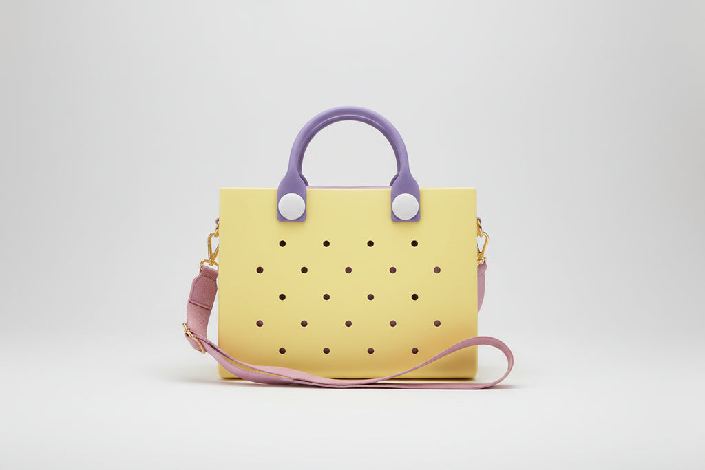 Yellow handbag with purple handles and strap on a light gray background