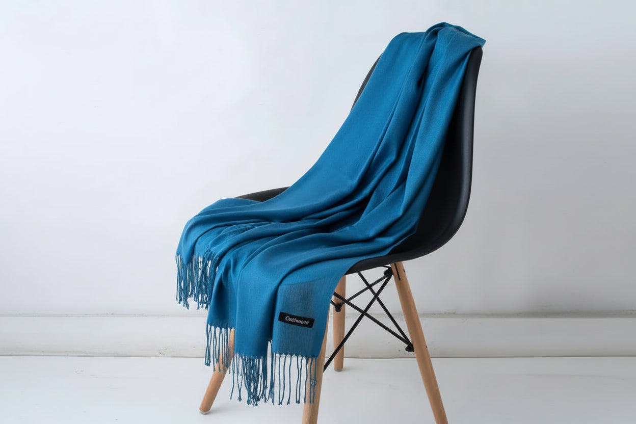 Blue throw blanket draped over a white chair with a plant in the background