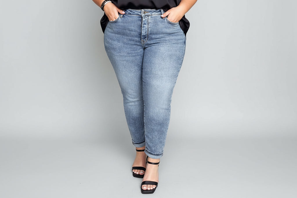 Person wearing a black top and blue jeans standing in front of a door.