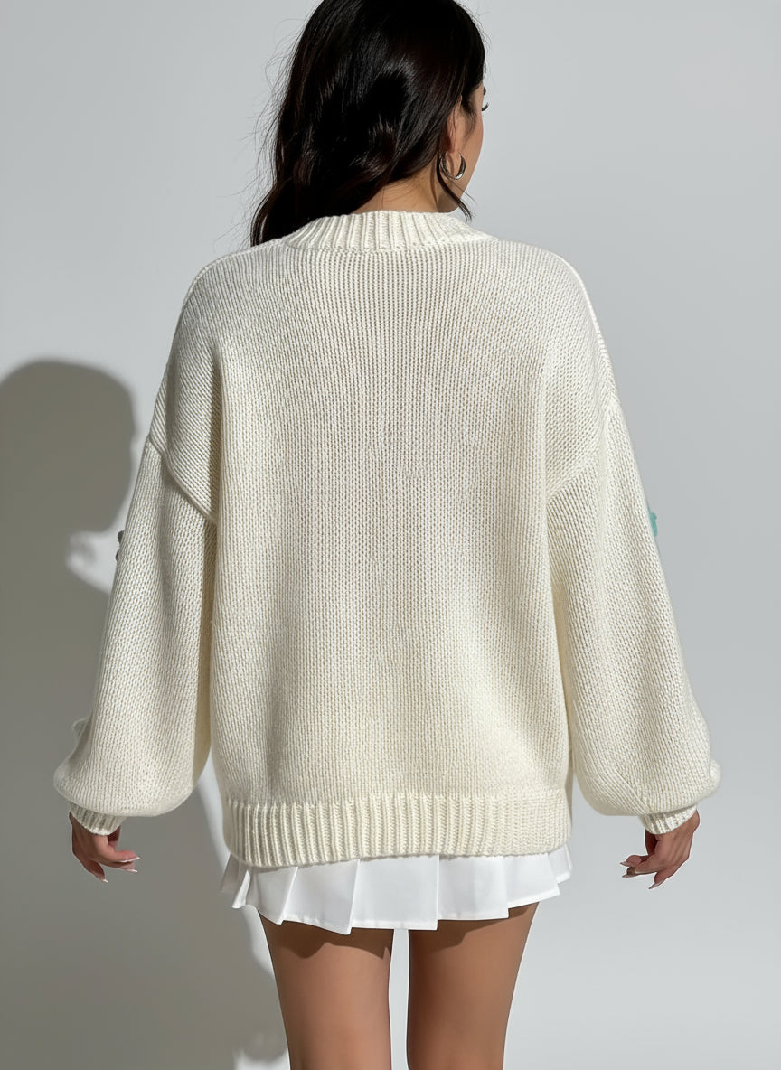 Person wearing a cream-colored sweater against a white wall