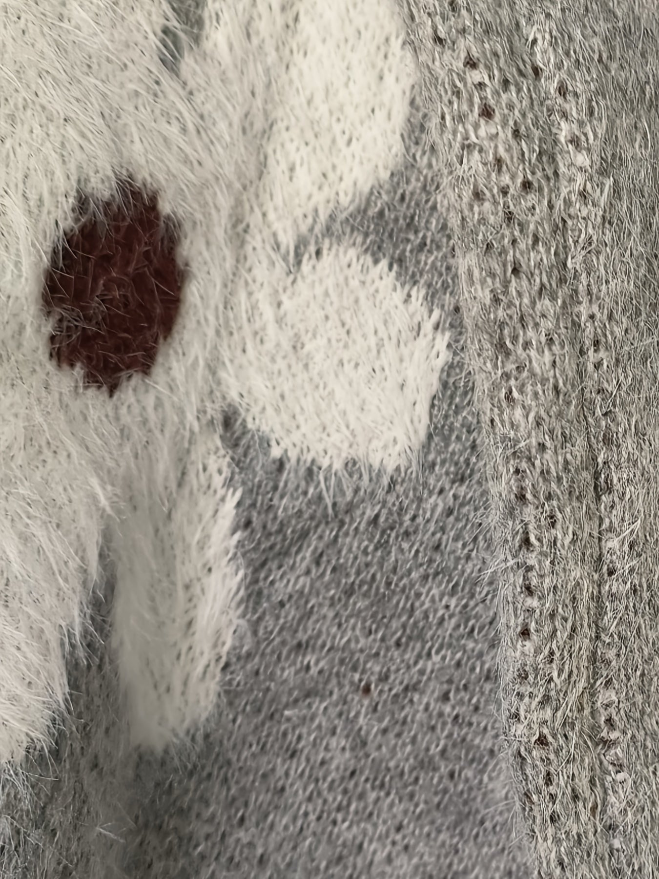Close-up of a knitted fabric with a pattern of white, gray, and brown.