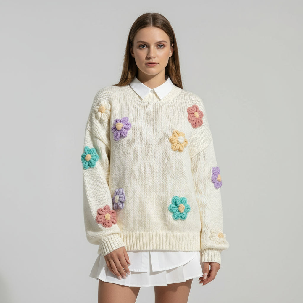 White sweater with colorful flower appliqués on a plain background