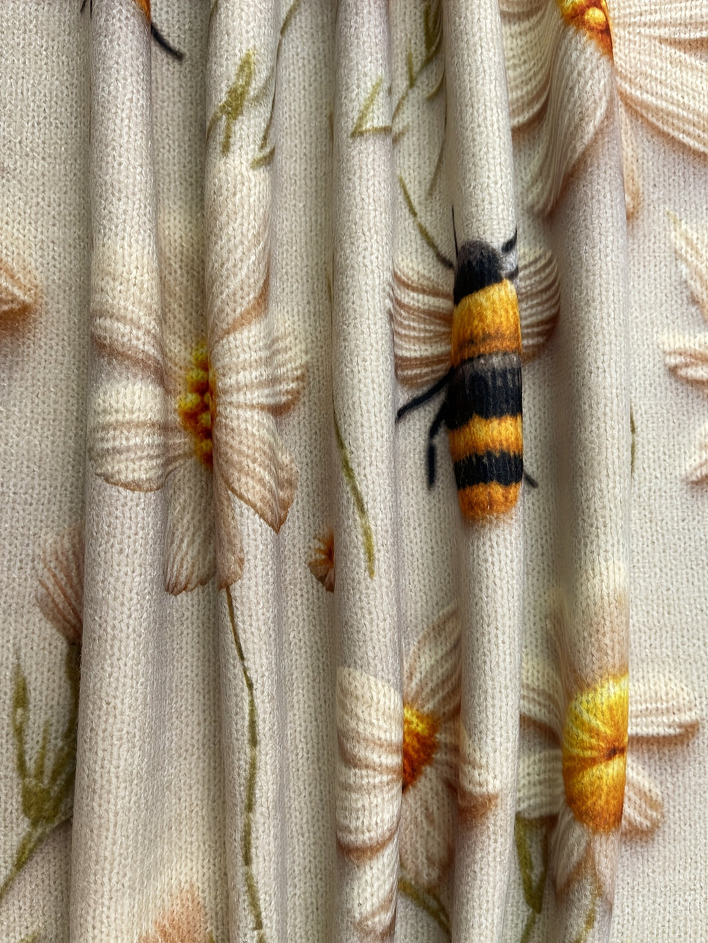 Close-up of a bee on floral fabric with a yellow and black striped pattern.
