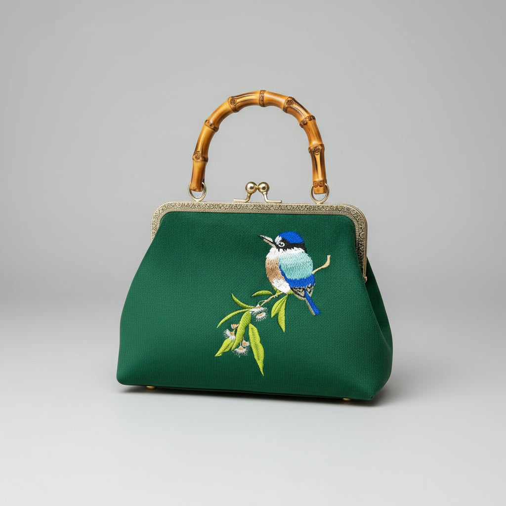Green handbag with bird embroidery held by a hand against a red and gold fabric background