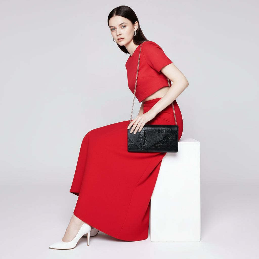Person wearing a red outfit holding a black clutch bag with a chain strap.