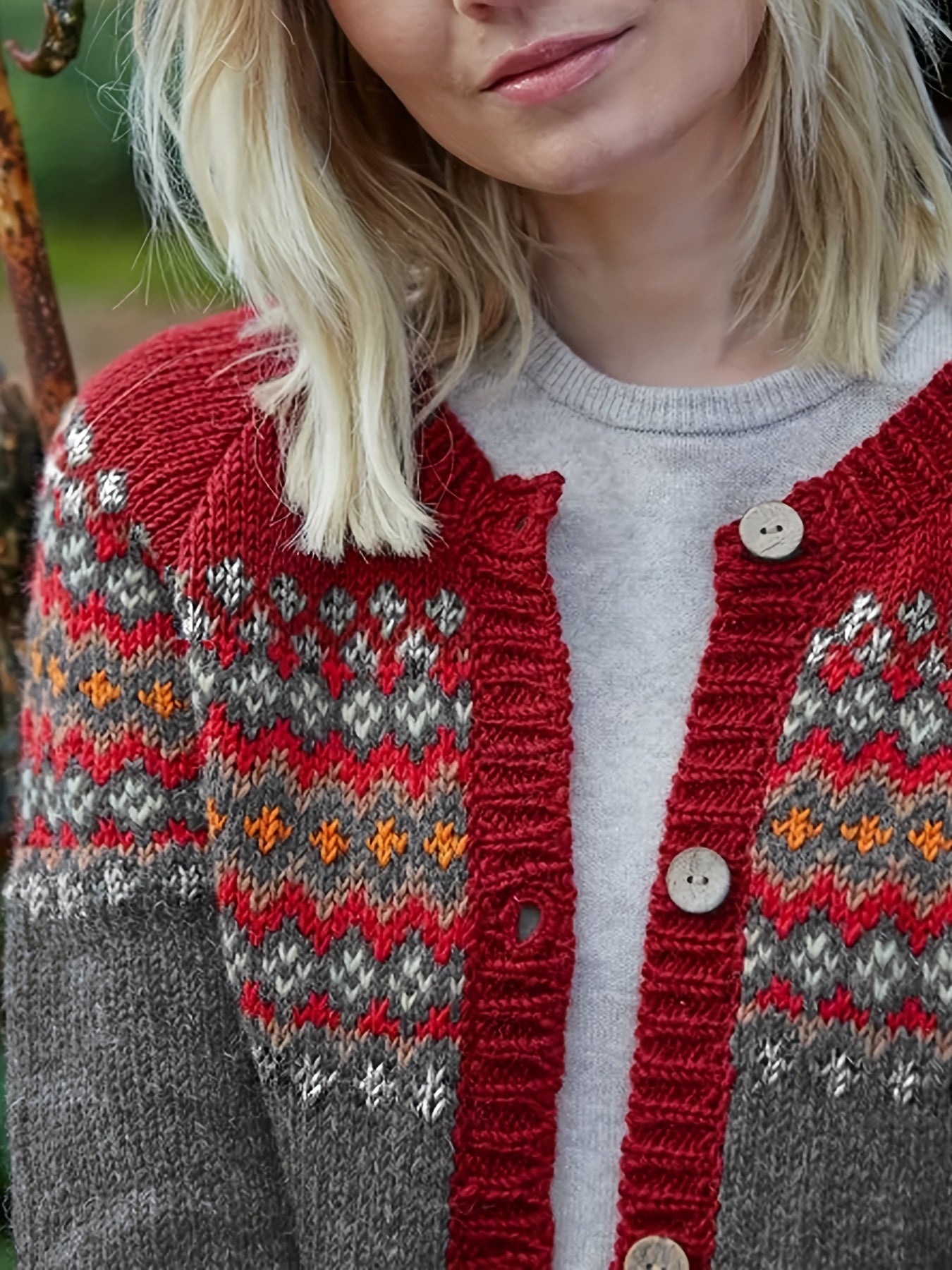 Person wearing a red and gray patterned cardigan with a blurred background
