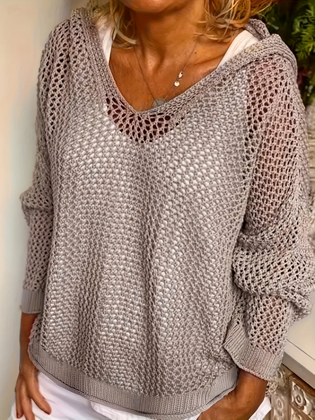 Person wearing a textured gray sweater with a white shirt underneath.