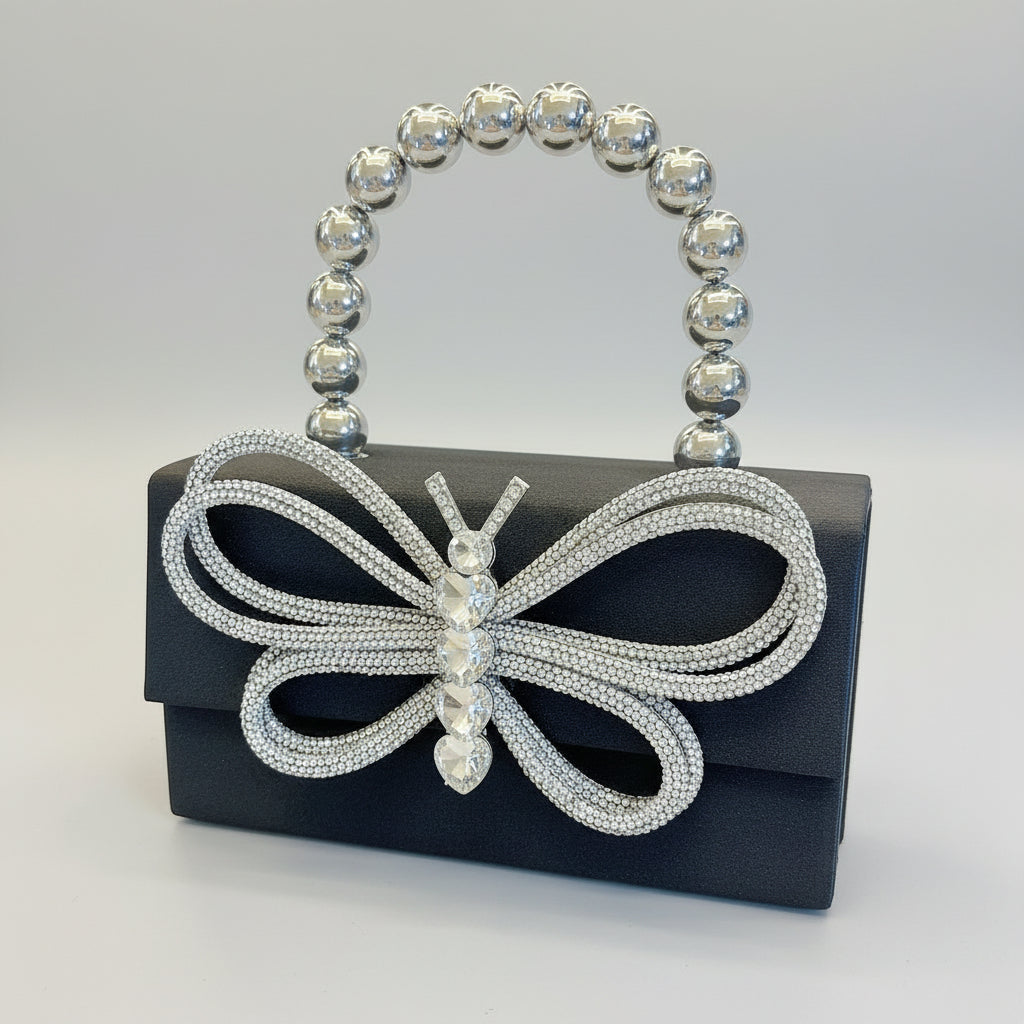 Butterfly-shaped handbag with beaded handle held by a hand against a neutral background