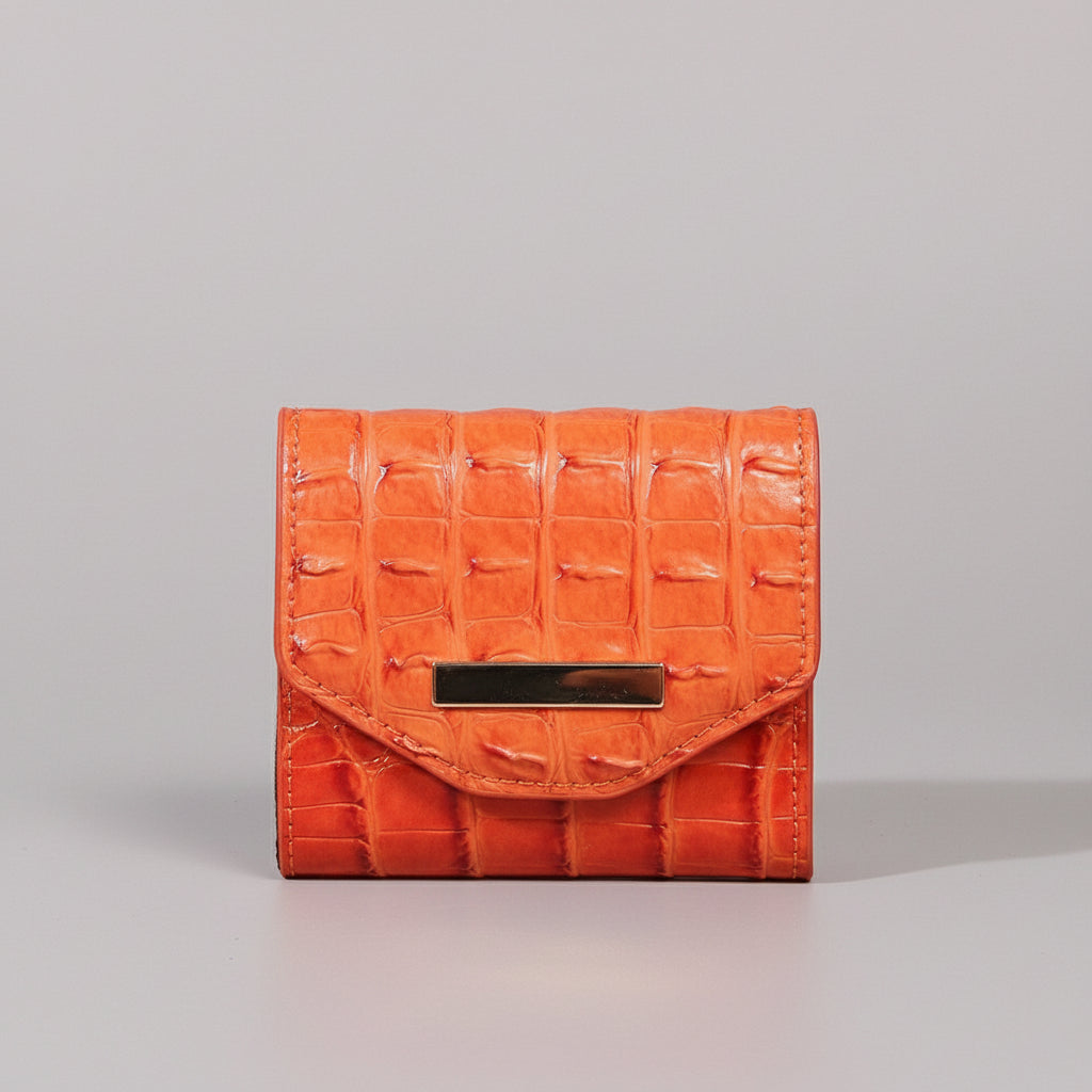 Orange textured wallet with a gold clasp on a light gray surface.