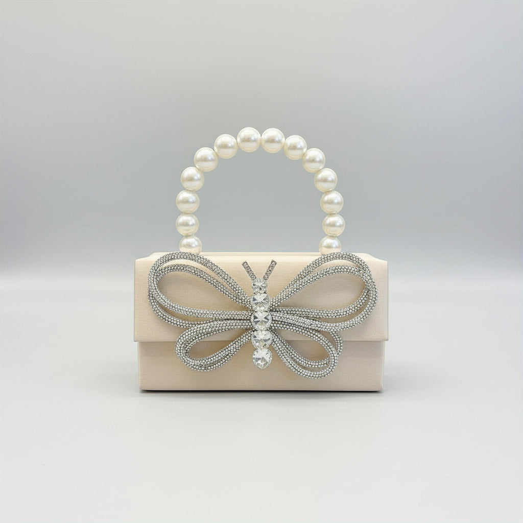 Handbag with butterfly design and beaded handle held by a hand against a neutral background