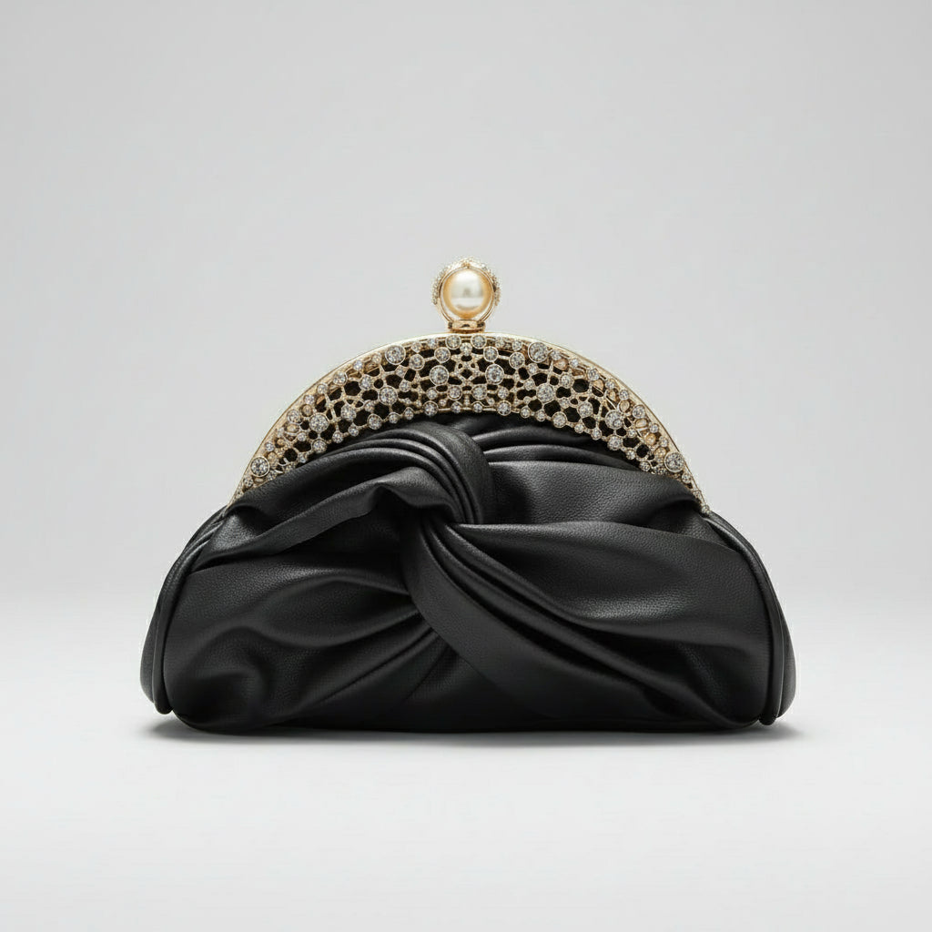 Black clutch with gold embellishments held by a hand against a neutral background